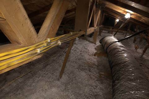 Cable runs stapled across attic framing above blown-in insulation
