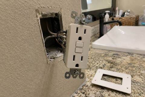 Ground-fault receptacle pulled forward from a wall box, test and reset buttons facing out