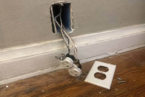 Receptacle pulled forward from a wall box with the wiring loose in front of it