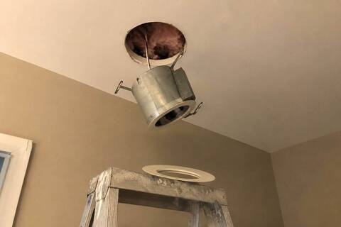 Recessed light housing hanging below a ceiling opening with the trim off
