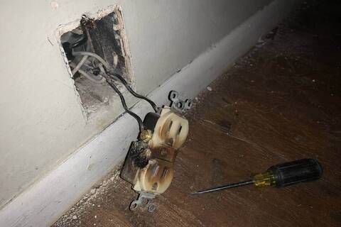 Discolored receptacle out of a wall box with darkened terminal screws