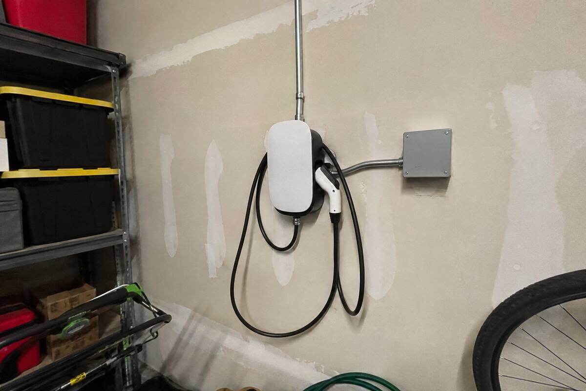 Wall-mounted vehicle charging unit in a garage with conduit running up the wall
