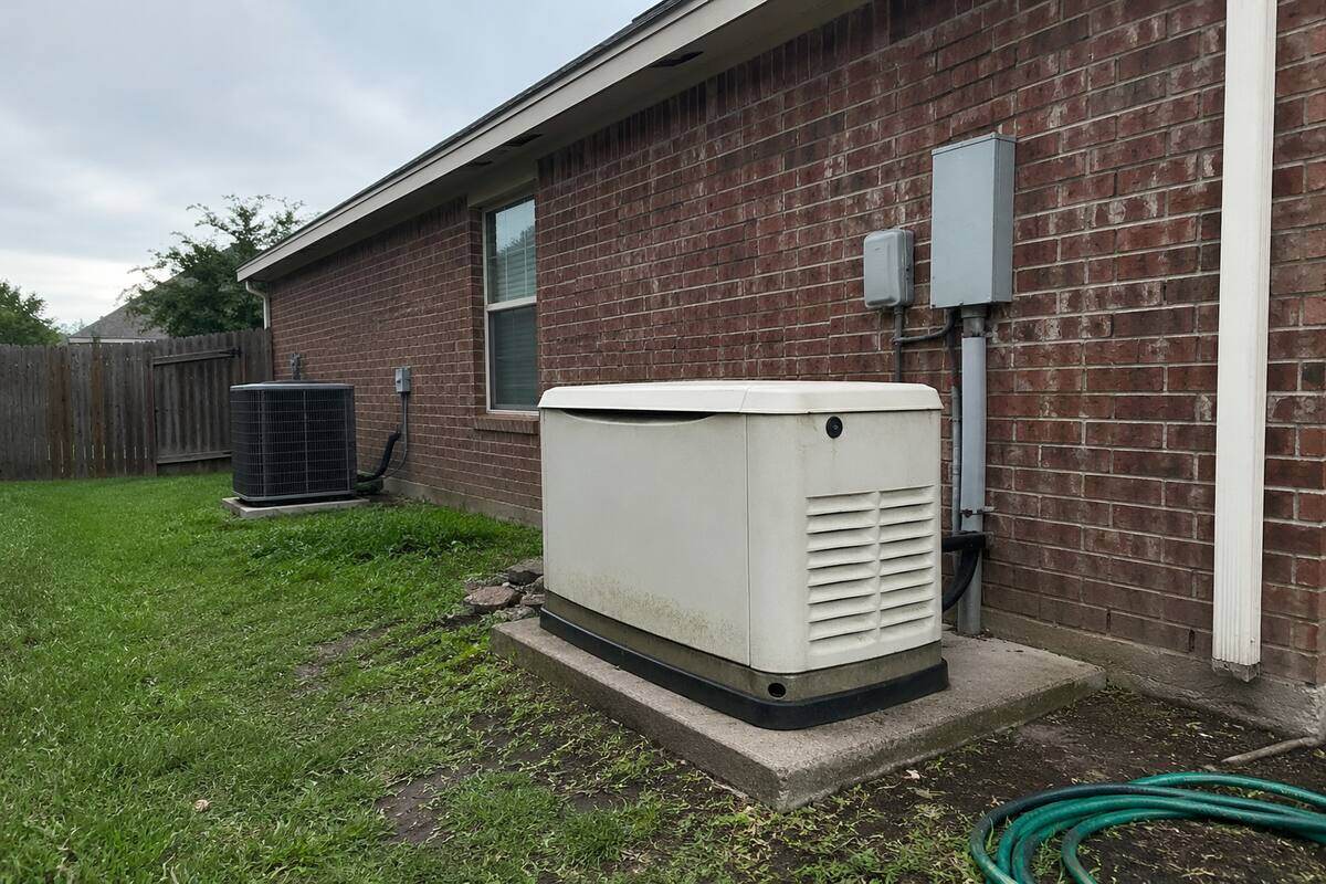 Standby generator enclosure on a concrete pad beside a brick wall