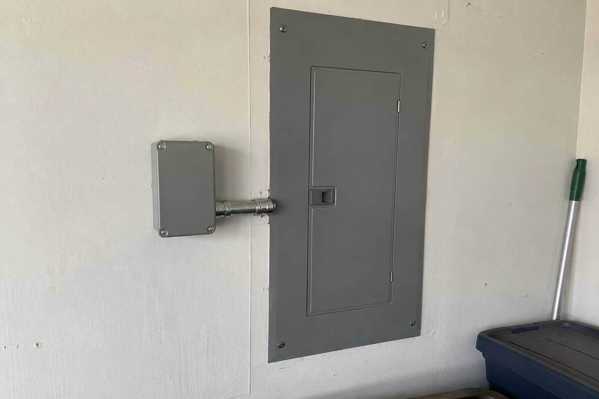 Small surge protective device mounted on a wall beside a panel with a short conduit nipple between them